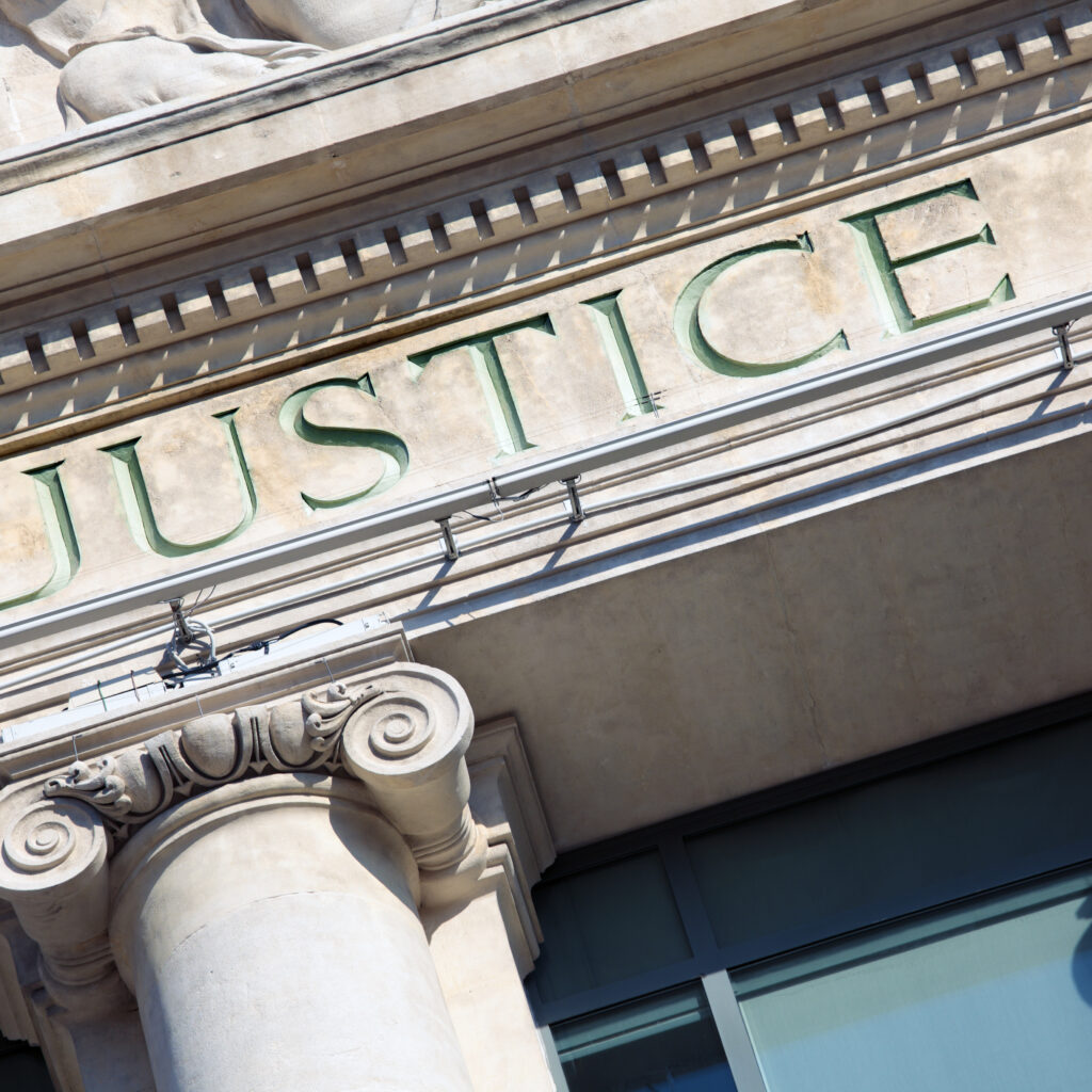 The word Justice on a Courtroom Building.